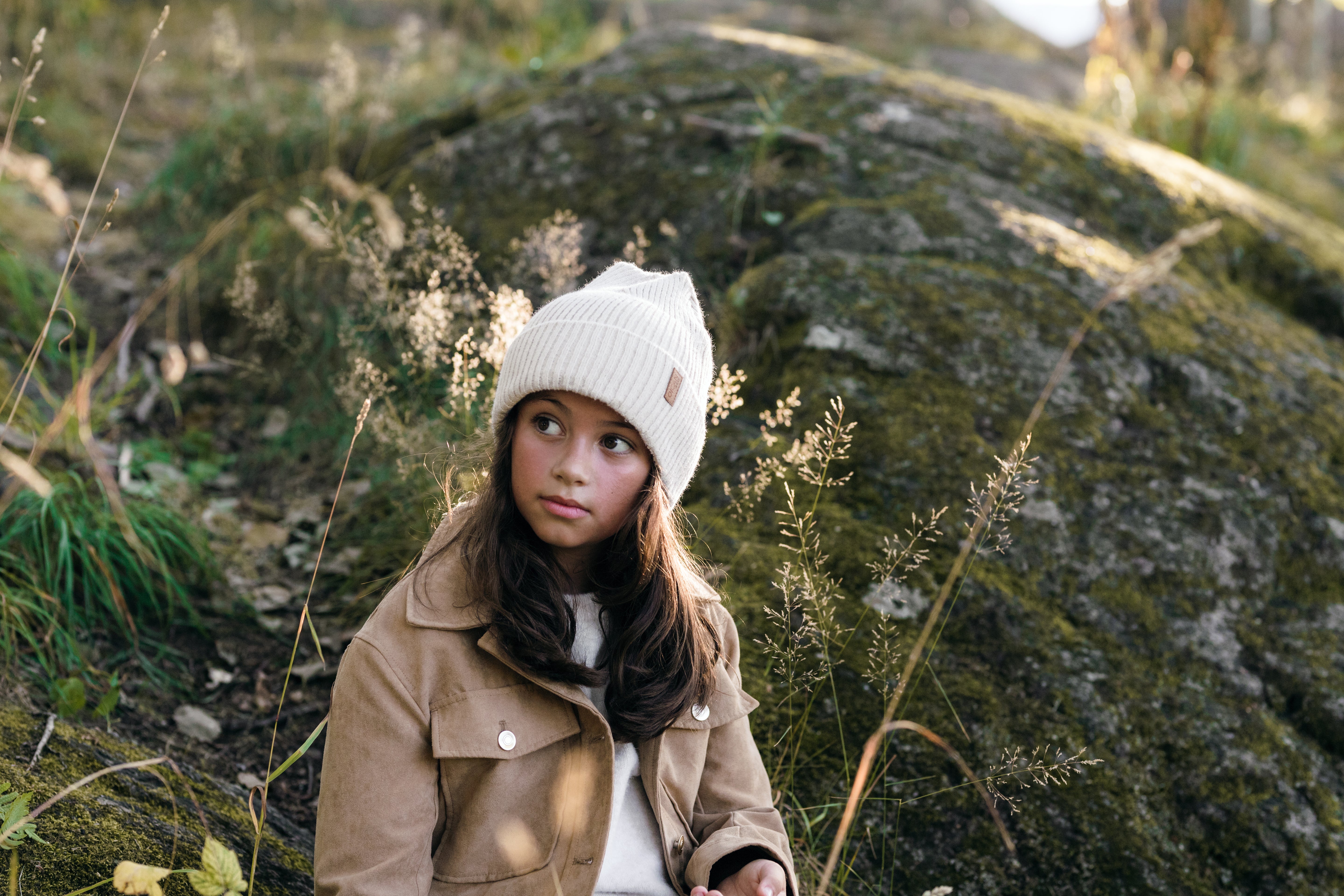 En flicka med brunt hår bär Ivory SafeHat ute i naturen.