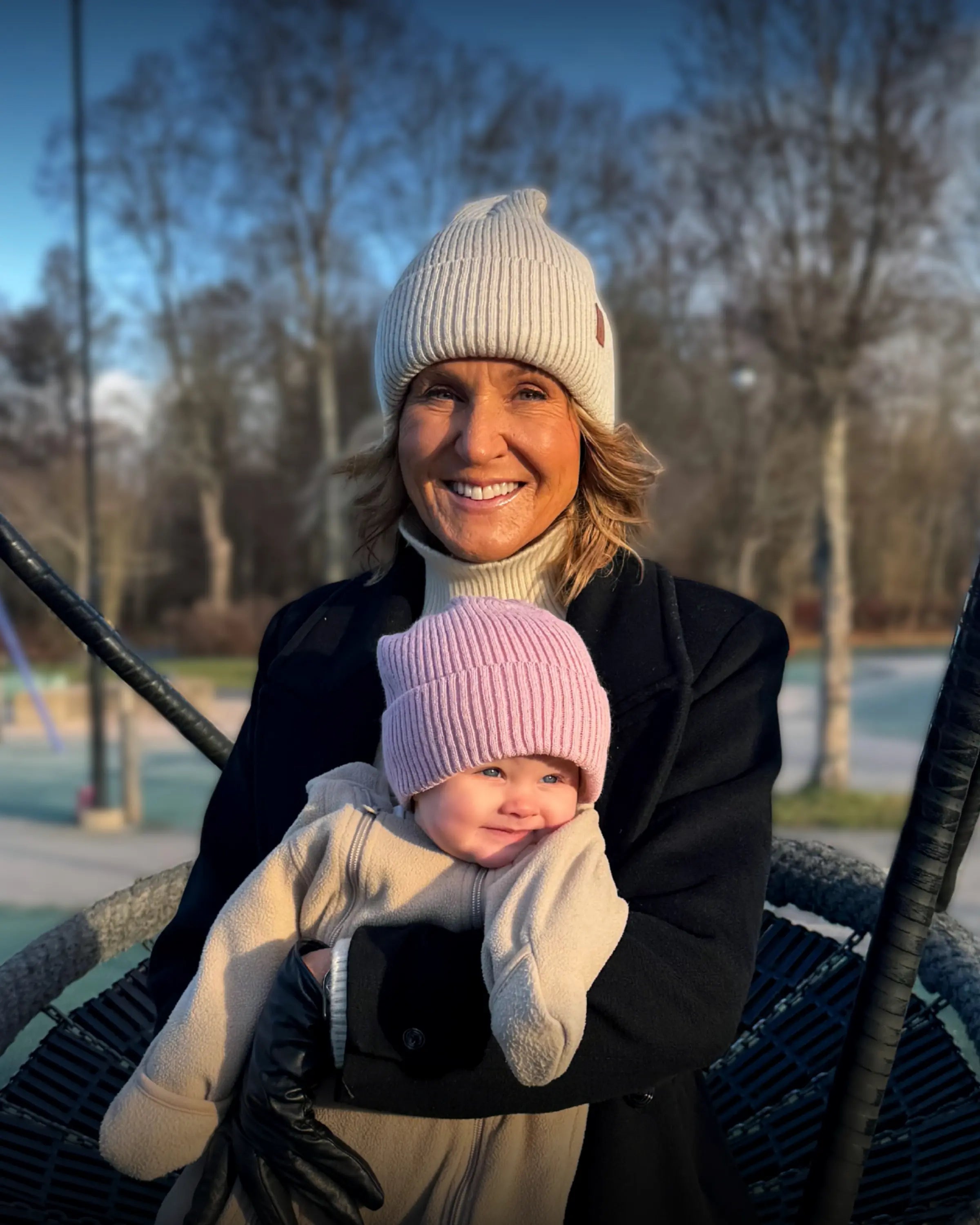 Kvinna med Ivory och barn med Soft Pink SafeHats i en gunga