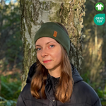 Tjej med grönt pannband från OICAN i skogen. Två ikoner i högra hörnet.