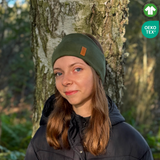 Tjej med grönt pannband från OICAN i skogen. Två ikoner i högra hörnet.