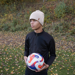 En kille bär en SafeHat sport i Sandy Beige och håller i en fotboll