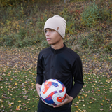 En kille bär en SafeHat sport i Sandy Beige och håller i en fotboll