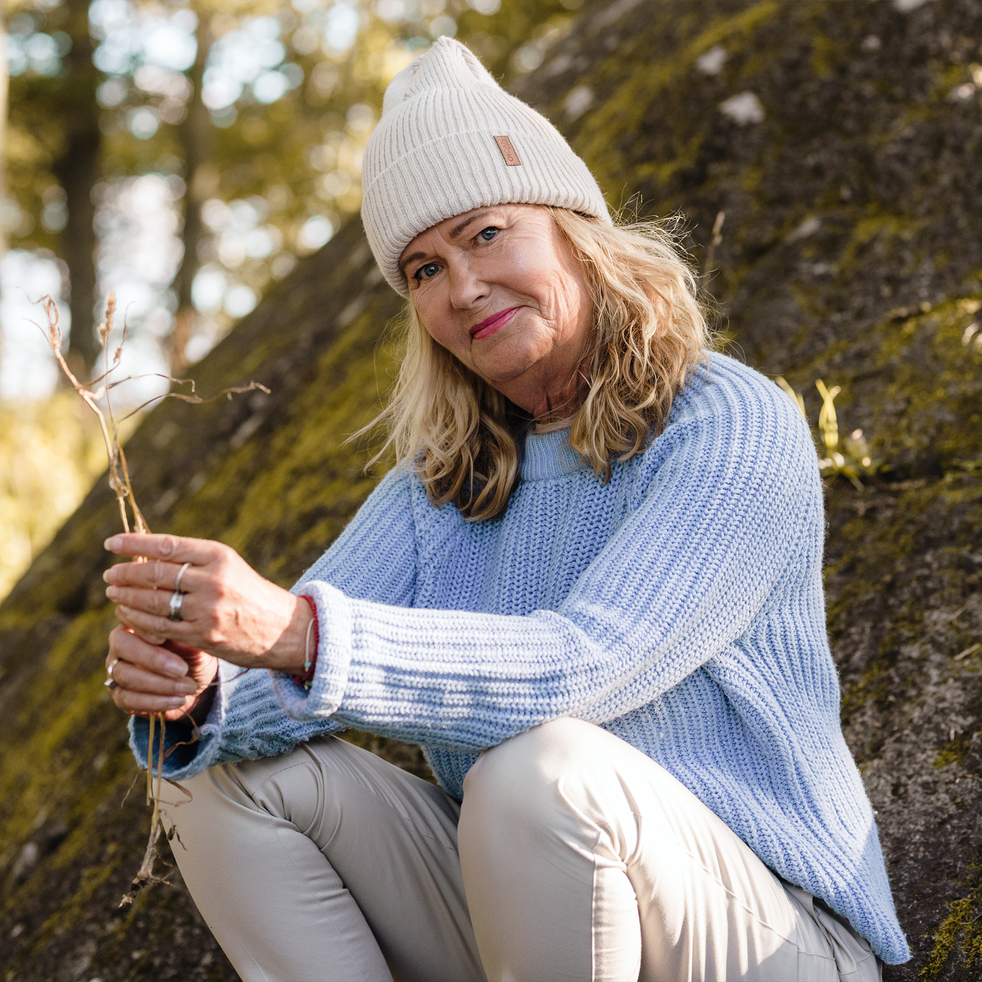 Dam bär Ivory SafeHat med blå stickad tröja i skogen