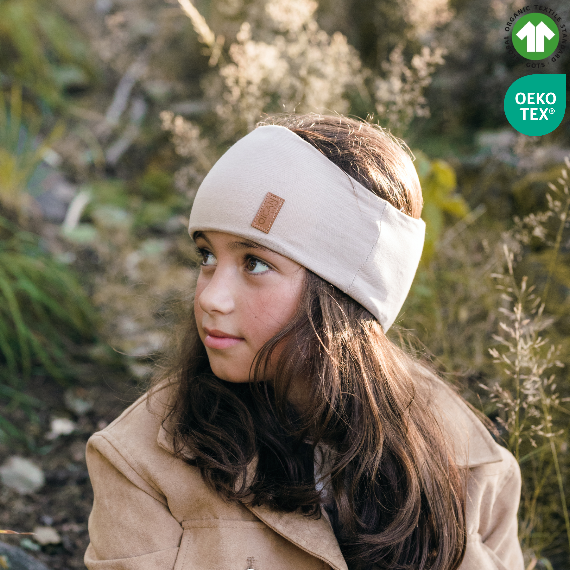 Flicka med beige pannband, sitter utomhus