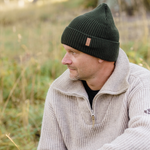 Man bär forest green safehat i naturen, bild tagen från sidan.