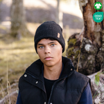 Kille bär svart stickad mössa i naturen