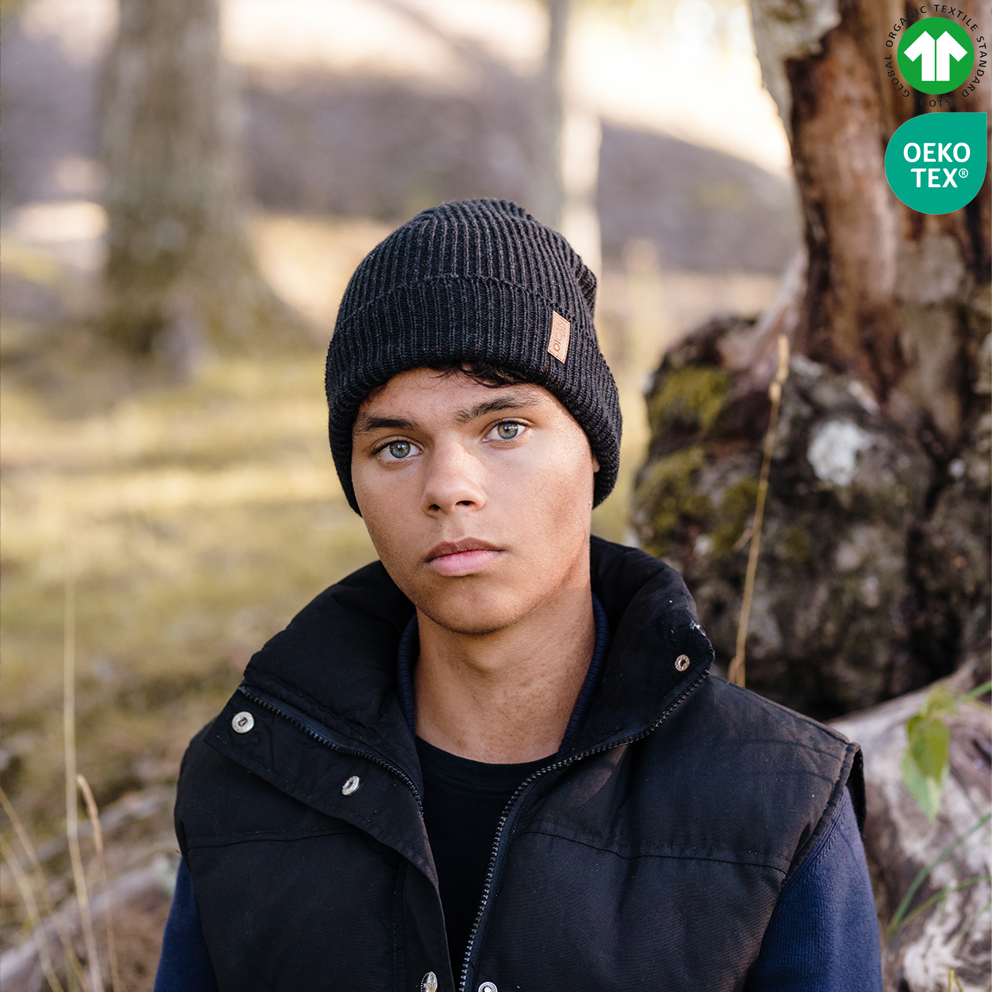 Kille bär svart stickad mössa i naturen