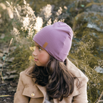 Flicka i naturen kollar åt sidan med en lila safehat på huvudet