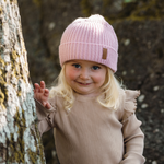 Flicka bär safehat soft pink i skogen, hon ser busig ut